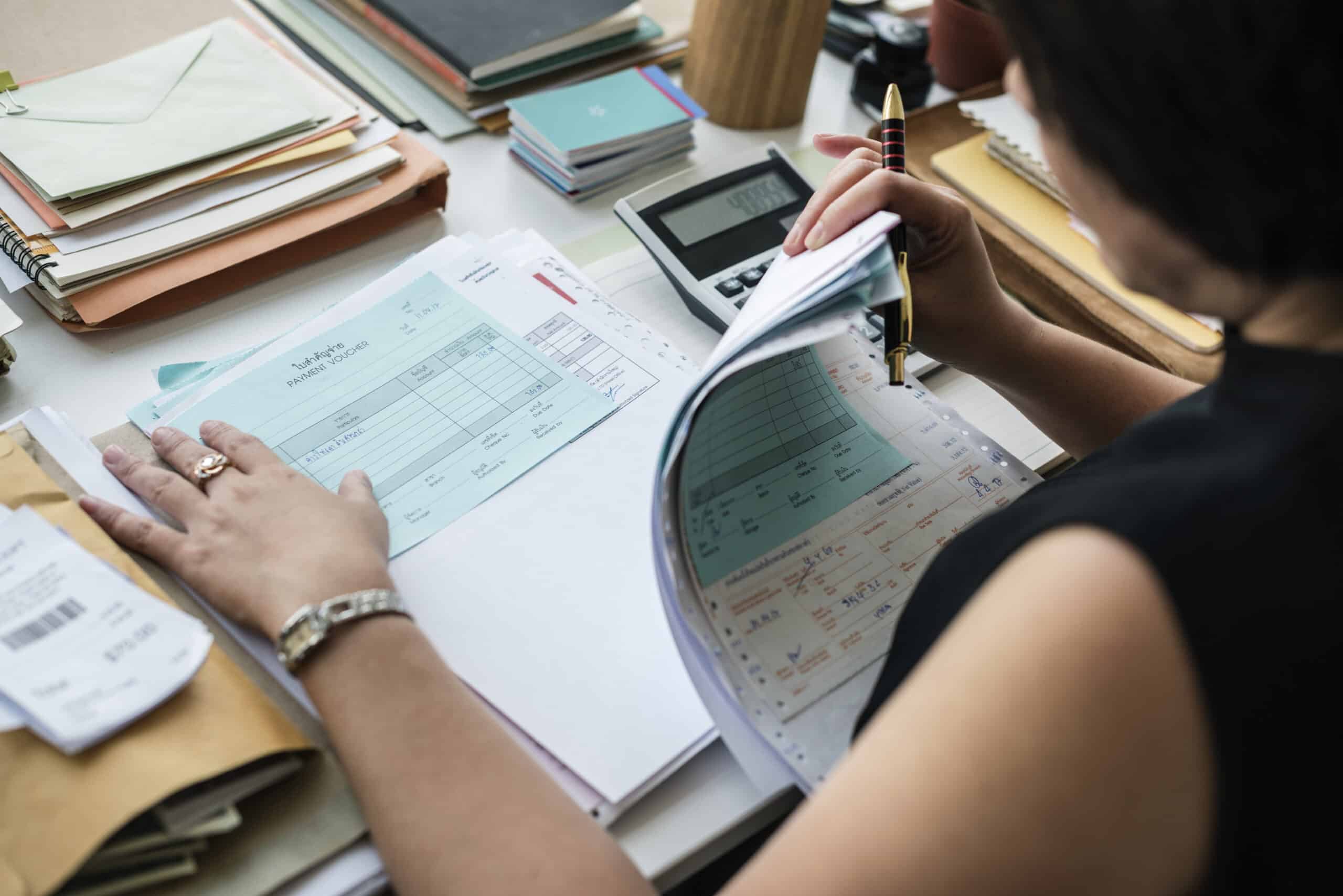 Asian woman working through paperwork for bookkeeping for her business