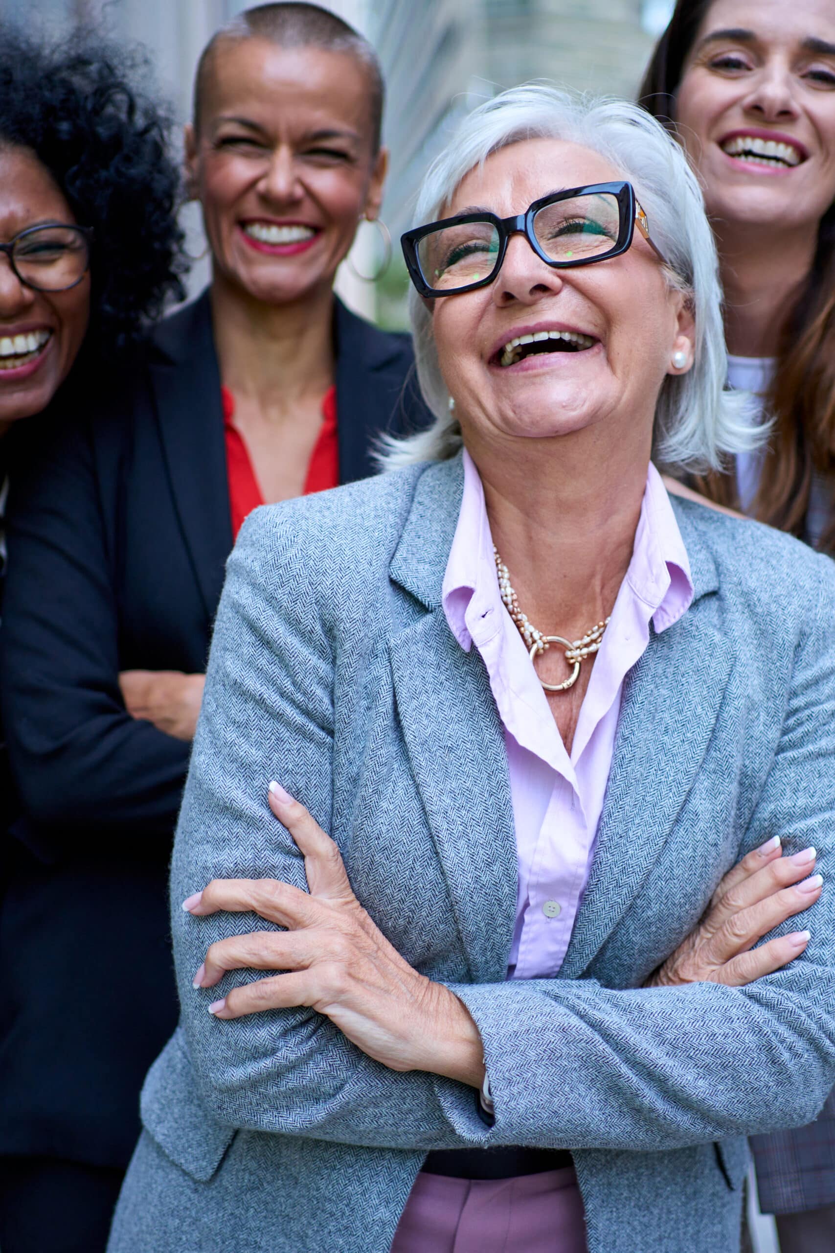 Vertical portrait. Group of multiracial and diverse ages smiling business only women in formal suit. Cheerful businesswomen looking at camera outdoor. Empowered, successful, professional female worker