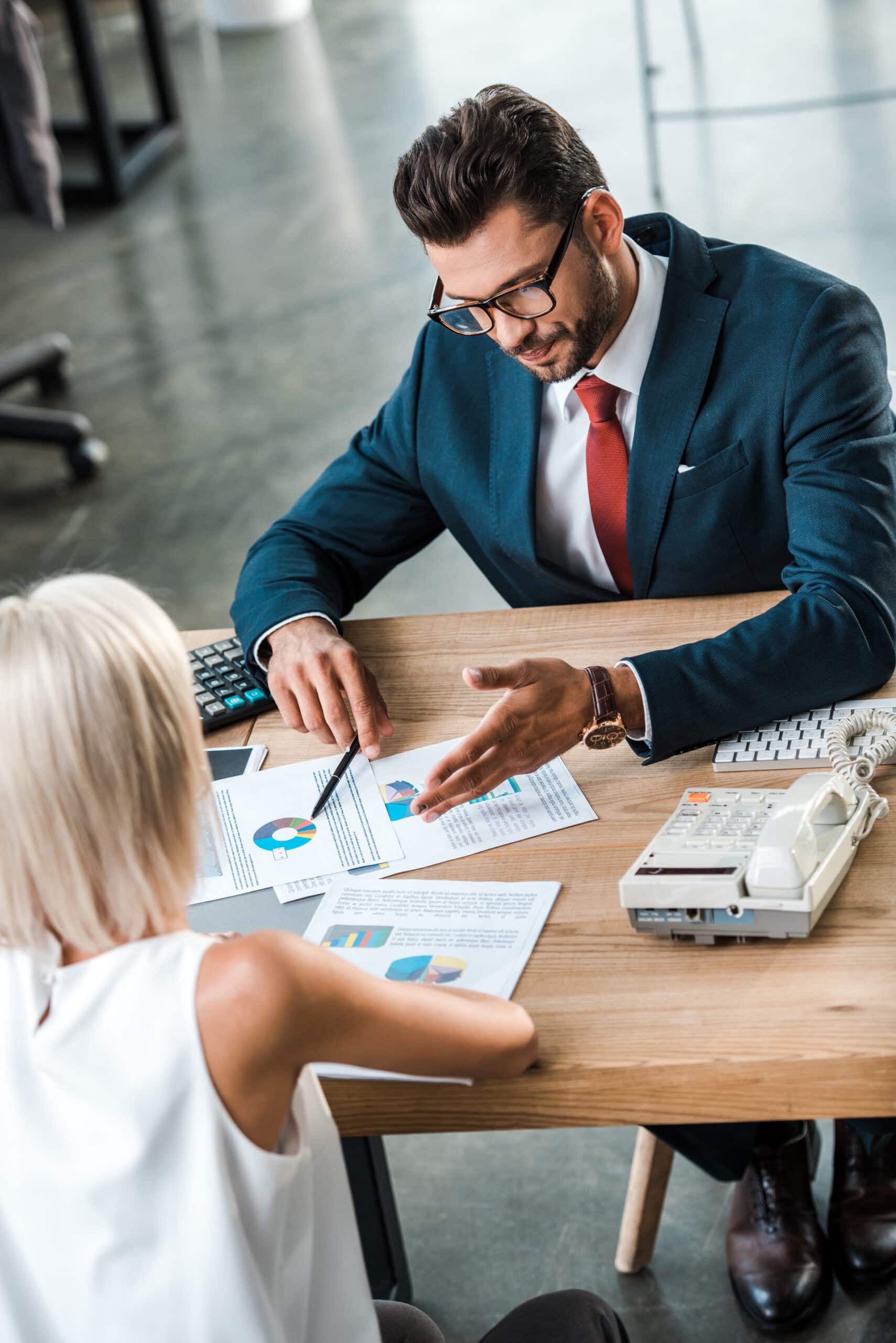 selective focus of handsome businessman in glasses gesturing near blonde woman